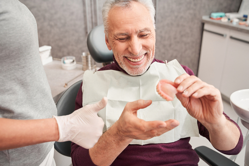 older man holding dentures